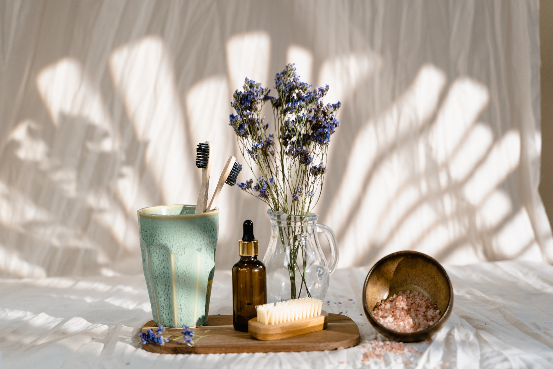 green cup, a bottle of essential oil, lavender flowers,